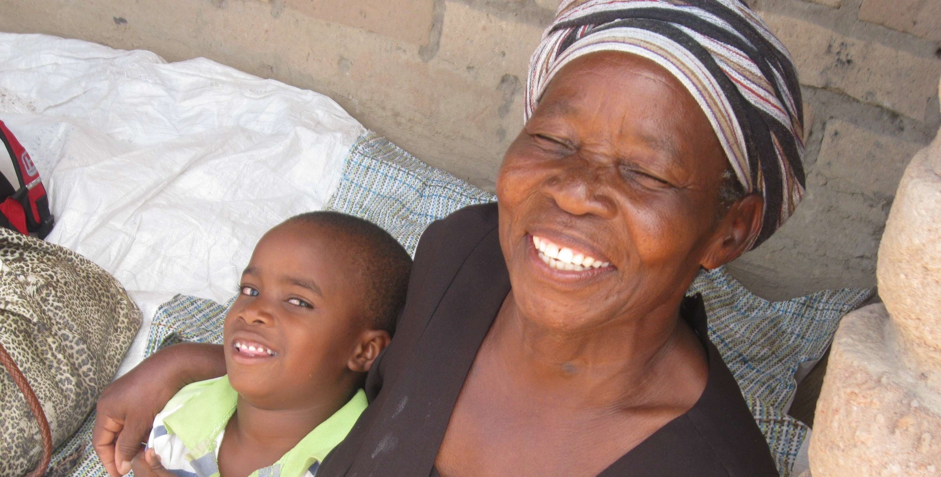 A young boy and his grandmother, both smiling at the camera